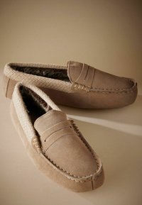 Jasnobrązowe zamszowe loafersy z teksturowanym beżowym wykończeniem i sztucznym futerkiem w środku, z dekoracyjnym ściegem i zaokrąglonym noskiem.
