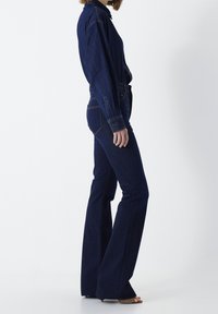 Camisa de mezclilla azul oscuro y jeans de pierna ancha, ambos con una textura suave, cuello abotonado y detalles de costura visibles.