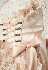 Corsage traditionnel rose pâle avec laçage à l’avant, manches en dentelle, détails floraux brodés et large nœud en satin à la taille.