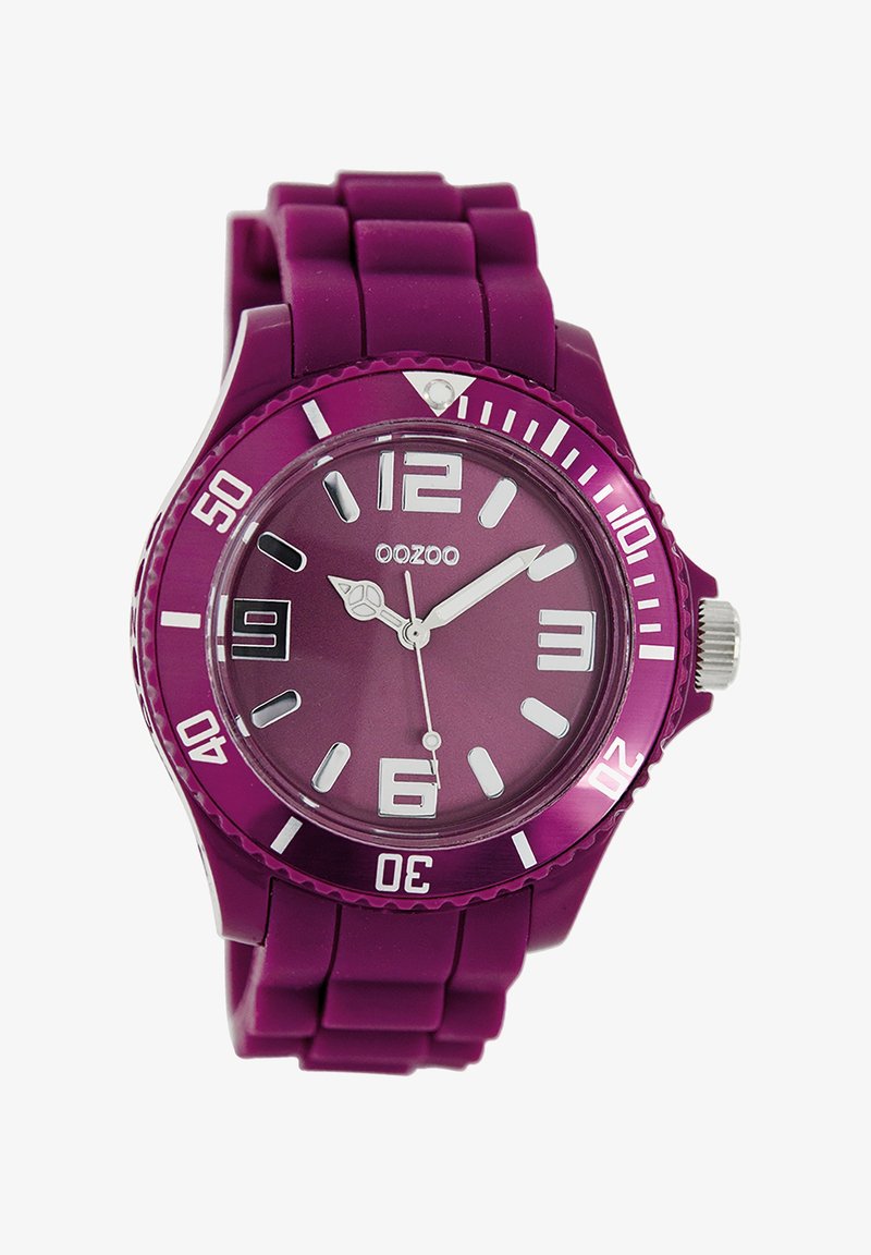Montre en silicone violet avec un boîtier rond, des index d'heure blancs contrastants et un bracelet texturé. Présente une couronne imposante et un design minimaliste.