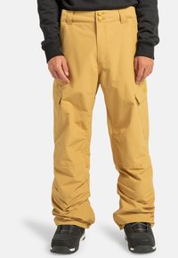 Pantaloni da neve gialli impermeabili con vestibilità ampia, dotati di tasche cargo e chiusura a due bottoni. Tessuto testurizzato, progettato per l'uso all'aperto.