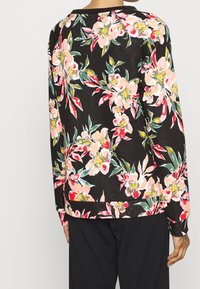 Bloemen sweatshirt met een zwarte achtergrond met roze en rode bloemen, groene bladeren en een losse pasvorm. Gestructureerde stof met geribbelde manchetten.