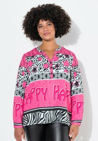 Kleurrijke blouse met lange mouwen in een roze en zwarte dierenprint, met een knoopsluiting bij de hals en vetgedrukte tekst "Happy" in het roze.