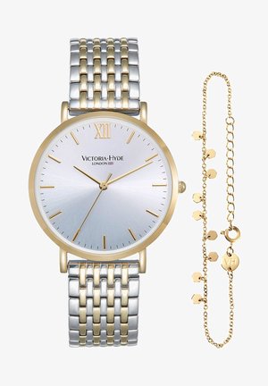 Orologio da polso con cassa rotonda in tonalità argento e oro, quadrante in argento spazzolato, indici a bastone e bracciale a maglia. Include una catena in oro abbinata.