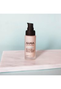 Siero Illuminante e di Ringiovanimento AHAVA Age Control in una bottiglia di vetro opaco con pompa nera, etichettato con testo in nero e teal, 30 ml.