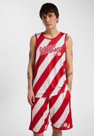 Junge Person trägt rot-weiß diagonal gestreiftes ärmelloses Oberteil und passende Shorts mit dem Schriftzug und den Logos „Danish Dynamite“.