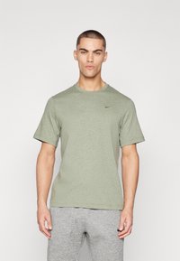 Olíva zöld, rövid ujjú póló puha anyagból, kerek nyakkivágással és diszkrét fekete Nike logóval a mellkason.