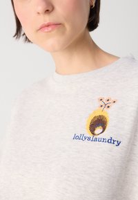Svietlosivý sveter s rebrovaným výstrihom, so živou výšivkou kvetu a abstraktného tvaru, značky "lollyslaundry."