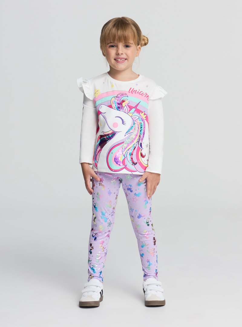 Maglietta bianca a maniche lunghe con spalle arricciate e una colorata grafica di unicorno, abbinata a leggings viola con motivi di stelle multicolori.