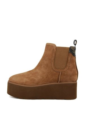 Stivale Chelsea in suede marrone con una suola piatta spessa, pannelli laterali elastici e punta arrotondata. Presenta un'etichetta per il pull e un dettaglio di branding discreto.