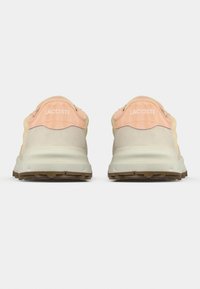 Lacoste sneakers with a beige suede and mesh upper, pink accents at heel, and beige rubber sole. "LACOSTE" printed on heel tab.