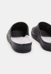 Fekete slip-on cipők perforált felső résszel, párnázott talppal és gumitalppal, sima textúrával.