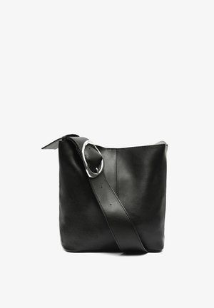 Černá kožená kabelka přes rameno s hladkým povrchem, širokým popruhem a výrazným stříbrným kováním. Minimalistický design, neformovitý tvar.