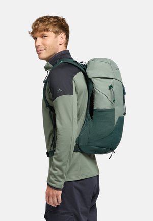 Uno zaino da trekking verde presenta un design aerodinamico con accenti in rete, spallacci regolabili e una tasca con zip sulla parte anteriore.
