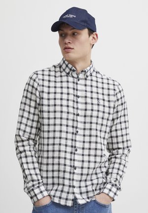 Black and white checked long-sleeve shirt with a button-down collar and a small embroidered logo. Denim cap worn at an angle.