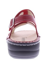 Rote Ledersandalen mit einer schwarzen Plattform. Verfügt über doppelte Riemen und eine silberne Schnalle, flachen Fußbett und weiße Nähte entlang der Kante.