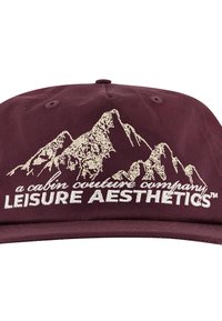 Tummanpunainen lippalakki, jossa on kirjailtu vuorimaisema ja teksti "a cabin culture company LEISURE AESTHETICS™" kermanvärisenä.
