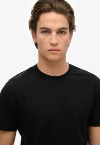 Sort bomulds t-shirt med rund halsudskæring og korte ærmer, der har en glat tekstur og en tætsiddende pasform. Ingen mønstre eller hardware synligt.