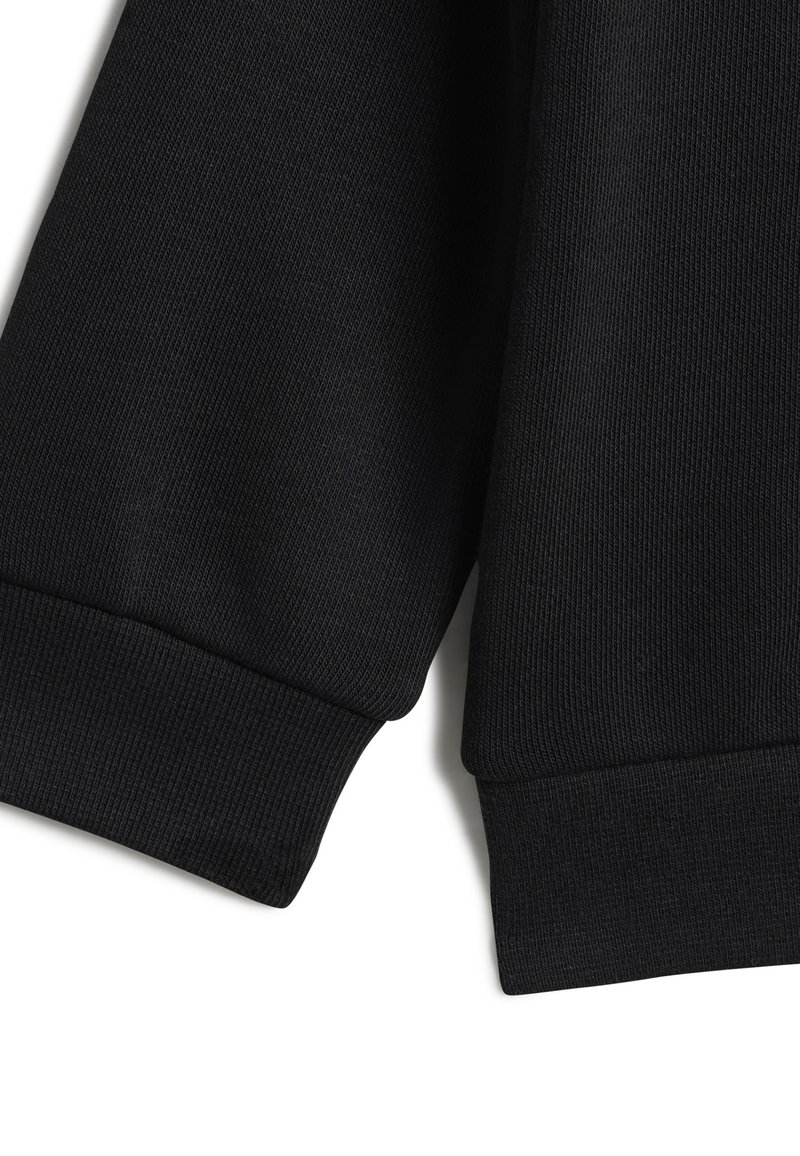 Tessuto di felpa nero a coste con una finitura testurizzata. I polsini e l'orlo sono anch'essi a coste, offrendo una vestibilità aderente.