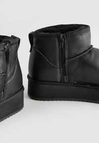 Schwarze Leder-Stiefeletten mit zwei seitlichen Reißverschlüssen, strukturierten Oberflächen und Gummisohlen. Sie verfügen über eine weiche Innenausstattung für zusätzlichen Komfort.
