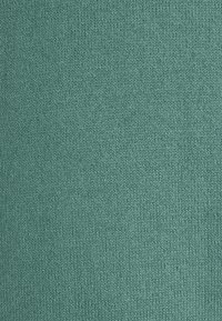 Tissu tricoté de couleur teal uni avec une surface texturée, présentant des coutures régulières et une apparence douce et confortable.