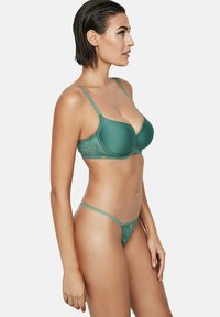 Ensemble de lingerie deux pièces en teal comprenant un soutien-gorge rembourré et un string. Le soutien-gorge possède des accents en dentelle, des bretelles ajustables et une texture lisse.