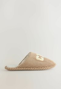 Beige kanka kengät, joissa on teksturoitu ribbimuotoilu, avoin takaosa ja pehmeä valkoinen vuori. Ominaisuuksiin kuuluu ruskea tikkaus ja vaaleansävyinen brodeerattu logo.