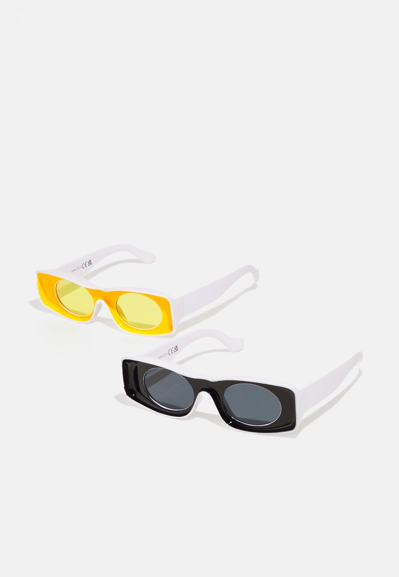 Dos pares de gafas de sol con montura blanca. Uno tiene lentes amarillos, el otro tiene lentes gris oscuro. Ambos tienen forma rectangular.