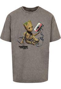 Grijze katoenen t-shirt met een geprinte graphic van een cartoon boomfiguur die een cassetteband vasthoudt, met zwarte accentlijnen en tekst eronder.