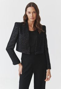 Schwarzer, taillierter Blazer aus strukturiertem Stoff mit Schulterpolstern und langen Ärmeln. Verfügt über einen einzelnen Knopfverschluss vorne.