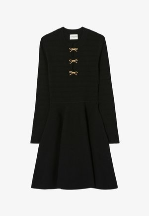 Abito lavorato a maglia nero a maniche lunghe con gonna svasata e tre piccoli bottoni a forma di fiocco dorato lungo il collo.