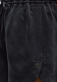 Μαύρα μαλακά υφασμάτινα σορτς με ελαστική μέση με πιέτες και μικρό λογότυπο Hugo κοντά στο τελείωμα.