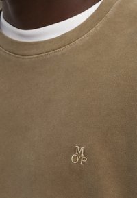 Khaki Baumwollsweatshirt mit Rundhalsausschnitt und gesticktem "M OP" Logo in Beige. Glatte Textur, minimalistisches Design, subtile Nähdetails.