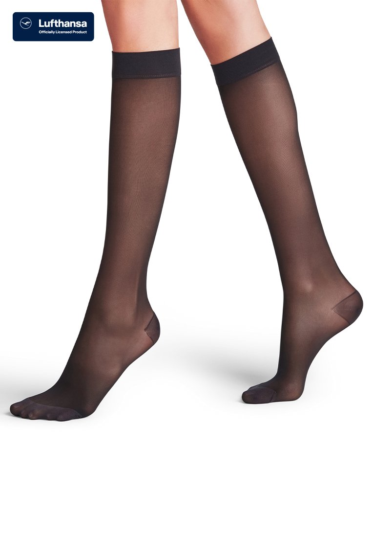Átlátszó fekete térdig érő kompressziós zoknit viselő lábak, a Lufthansa logóval, ami hivatalos engedélyezett terméket jelöl.
