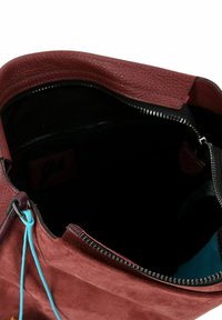Burgunderfarbene Wildledertasche mit glattem Lederbesatz, ausgestattet mit einem Reißverschluss und einem kontrastierenden blauen Innenraum. Inklusive einer dekorativen türkisfarbenen Krawatte.