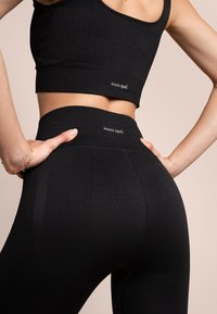 Czarny prążkowany sportowy crop top i legginsy z wysokim stanem, charakteryzujące się teksturowanym wykończeniem oraz małym logo "oceans apart" na pasku.
