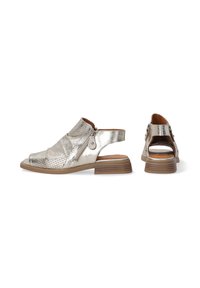Metalowe srebrne buty slingback o fakturowanym wykończeniu, z otwartym palcem i średnim brązowym obcasem. Posiadają zamek błyskawiczny i wycięcie w designie.