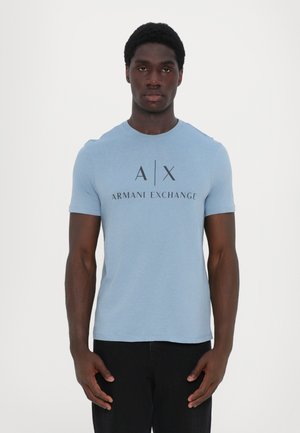 Lyst blå bomull T-skjorte med korte ermer, rund halsutringning og en stor svart logo som sier "A|X ARMANI EXCHANGE" på forsiden.