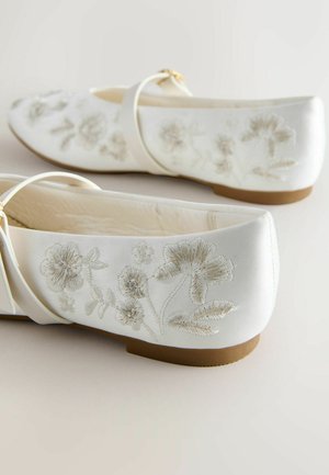 Balti satīna dzīvokļi ar sudraba un bēšu krāsas izšūtiem ziedu rakstiem. Tie ir arapaļoti noapaļotā purngalā un zemu brūnu zolē ar siksniņu.