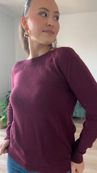 Pull en tricot bordeaux avec un col rond, un ourlet côtelé et des poignets. Caractérisé par une texture subtile et une coupe ajustée, associé à un jean en denim.
