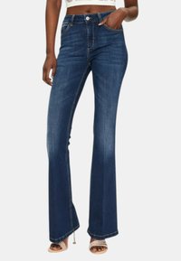 Jeans a zampa d'elefante blu scuro con vita media, caratterizzati da leggere sfumature, tasche anteriori e posteriori, e dettagli di cucitura a contrasto.