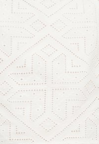 Tissu blanc présentant des motifs géométriques ajourés et de petits œillets, créant une texture et un intérêt visuel à travers tout le design.