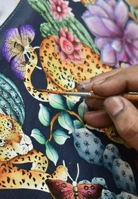 Leren kunstwerk met een kleurrijke leopard, bloemen en vlinders. Handgeschilderde details in levendige kleuren op een donkere achtergrond.