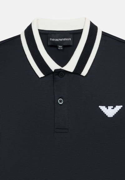 Μαύρο πόλο μπλουζάκι με γιακά με λευκές ρίγες, δύο μαύρα κουμπιά και λευκό λογότυπο αετού Emporio Armani στο στήθος.