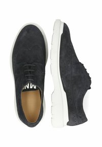 Mörkblå mockaskor med broguedetaljer, vit gummisula, snörningsdesign och slät foder. Har perforerade inslag.