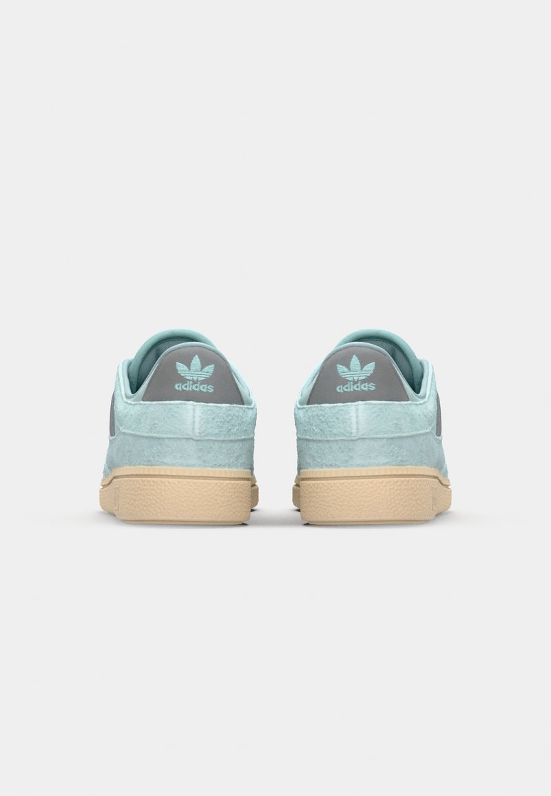 Helle blaue Wildledersneaker mit strukturierter Oberfläche, mit einem grauen Akzent auf der Rückseite und einer beige Gummisohle. Drei-Streifen-Logo sichtbar.
