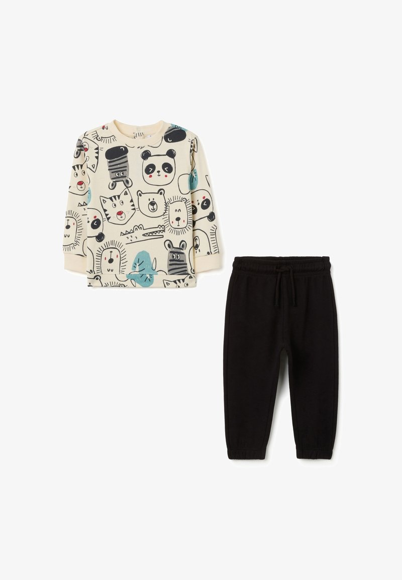 Kinderbekleidungsset mit einem langen cremefarbenen Oberteil mit Tierdruck und schwarzen Sweatpants mit einem elastischen Bund. Hergestellt aus weichem Baumwollmaterial.