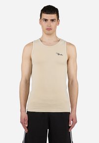 Beige ribbes tanktopp med rund halslinning og svart logo detalj på venstre bryst; kombinert med svarte teksturerte shorts. Glatt stoff.
