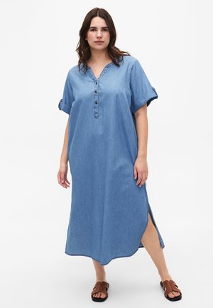 Denim shirtjurk, korte opgerolde mouwen, V-hals met knoopsluiting, zijsplitten, lichtblauwe kleur, soepele textuur, knielange uitvoering.
