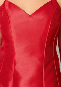 Vestido de satén rojo con un corpiño ajustado, escote en V y costuras en contraste. La tela tiene una textura suave y un ligero brillo.